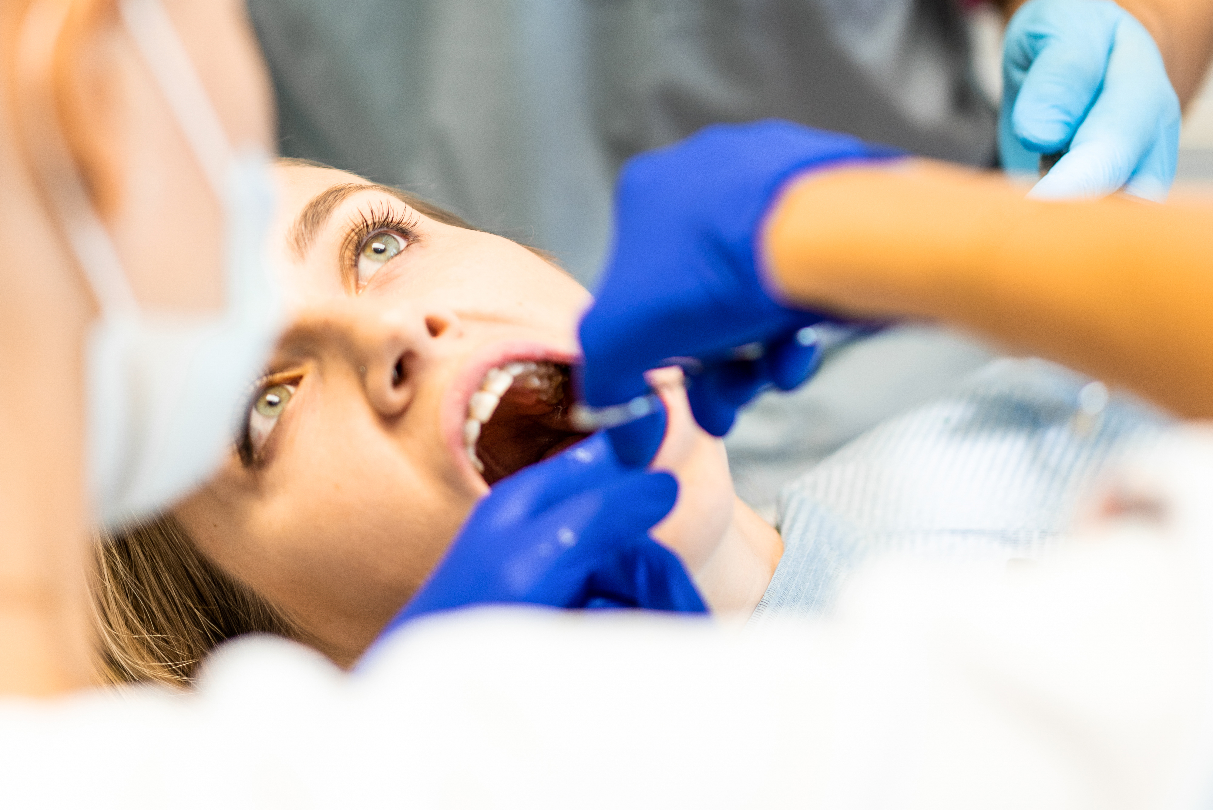 paciente joven con la boca abierta mientras el dentista le hace una examinación